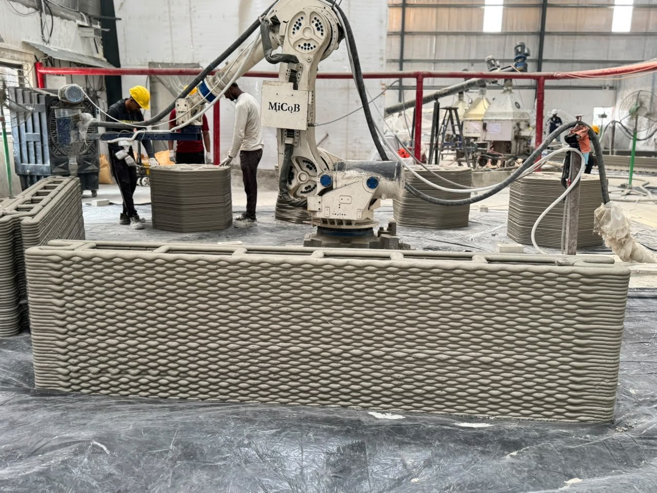 A printed wall panel taking shape layer by layer under robotic control.